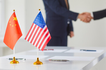 Flags of China and America against background of handshakes of political representatives of these...
