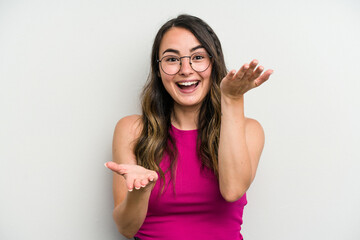 Young caucasian woman isolated on white background makes scale with arms, feels happy and confident.