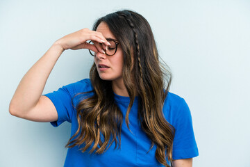 Young caucasian woman isolated on blue background having a head ache, touching front of the face.