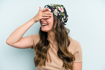 Young caucasian woman isolated on blue background covers eyes with hands, smiles broadly waiting for a surprise.