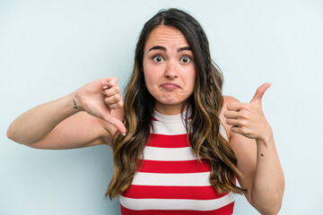 Fototapeta premium Young caucasian woman isolated on blue background showing thumbs up and thumbs down, difficult choose concept