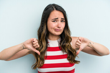 Fototapeta na wymiar Young caucasian woman isolated on blue background showing thumb down, disappointment concept.