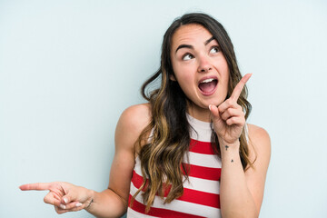 Young caucasian woman isolated on blue background pointing to different copy spaces, choosing one of them, showing with finger.