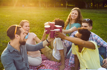 Diverse young friends celebrate start of summer vacation at outdoor party in park. Happy carefree...