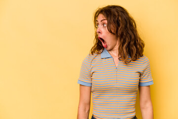 Young caucasian woman isolated on yellow background being shocked because of something she has seen.