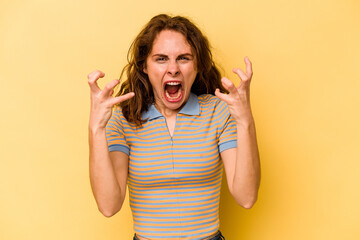 Young caucasian woman isolated on yellow background screaming with rage.