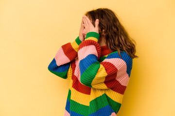 Young caucasian woman isolated on yellow background afraid covering eyes with hands.