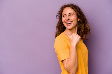 Young caucasian woman isolated on purple background points with thumb finger away, laughing and carefree.