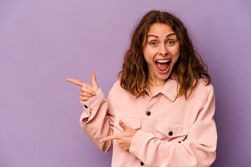 Young caucasian woman isolated on purple background excited pointing with forefingers away.