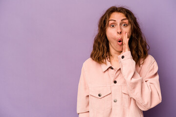 Young caucasian woman isolated on purple background is saying a secret hot braking news and looking aside