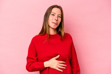 Obraz premium Young caucasian pregnant woman isolated on white background touches tummy, smiles gently, eating and satisfaction concept.