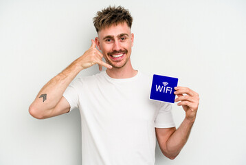 Young caucasian man holding wifi placard isolated on white background showing a mobile phone call gesture with fingers.