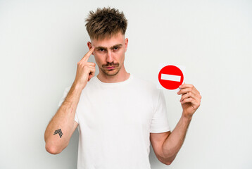 Young caucasian man holding a forbidden sign isolated on white background pointing temple with finger, thinking, focused on a task.