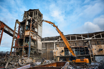 Fototapeta na wymiar Destroying of old industrial building by excavator destroyer