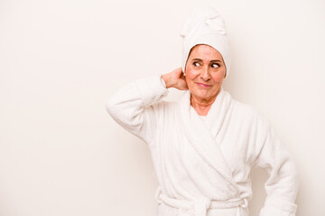 Middle age caucasian woman wearing a bathrobe isolated on white background touching back of head, thinking and making a choice.