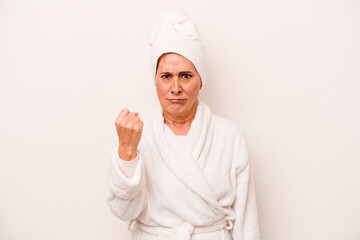 Middle age caucasian woman wearing a bathrobe isolated on white background showing fist to camera, aggressive facial expression.