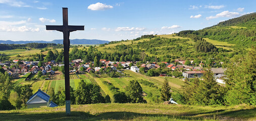 Three Christian wooden crosses in front of a village in the natural landscape in the foothills of...