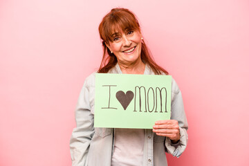 Fototapeta na wymiar Middle age caucasian woman holding I love mom placard isolated on pink background happy, smiling and cheerful.