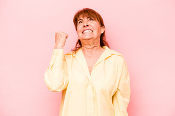 Middle age caucasian woman isolated on pink background celebrating a victory, passion and...