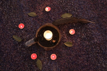Set-up for Cacao ceremony: glass of Raw Cacao, candles, bay leaves, flowers, feather, Palo santo,...