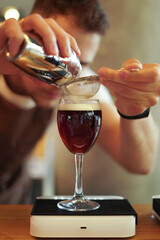 bartender pours spices into a cocktail