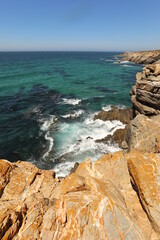 Turquoise sea on the rocky ocean beach with cliff on the ocean