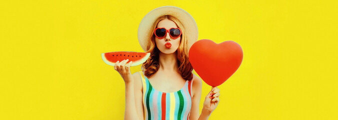 Portrait of beautiful young woman with slice of fresh watermelon and big red heart shaped balloon...