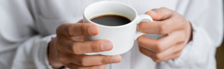 cropped view of woman holding cup of black coffee in hands, banner.