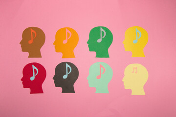 eight colorful paper head with musical notes in the heads on a pastel pink background, a day of music, a day of listening, happiness enjoyment on vacation and musical