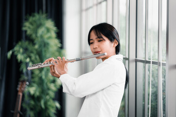 Young woman flutist performs on a musical instrument © thanmano