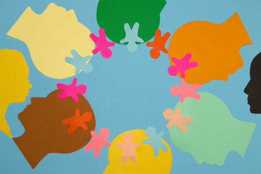 colorful paper head lined up in a circle around the circle that first and head lined up small colorful paper people in the middle copy space, pastel blue background looking at a man and a woman