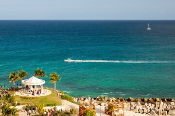 High angle shot of a coastline with a beach gazebo with jet skis and boats in the ocean