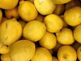 Stock photo of a large box with a bunch of lemons. Fresh juicy and sour citrus fruits, macro shot of yellow round lemons, ingredients for lemonade. For background, design, print
