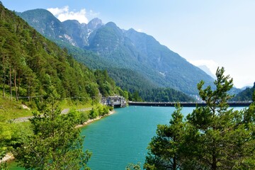 Fototapeta na wymiar View of Lago di Cadore lake in Veneto region and Belluno province in Italy and a hydroelectric power plant and mountains rising above the lake