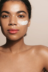 Vertical of african american woman with applied facial cream, skincare treatment for better skin...