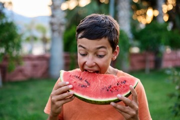 Cute boy eating watermelon outdoors in summer. Healthy eating seasonal berries and fruits. High quality photo