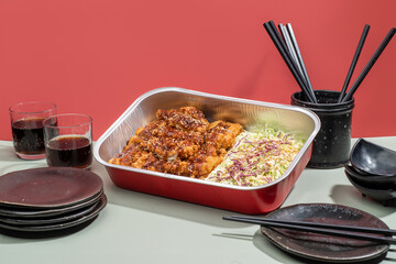 PORK KATSU food tray with salad, drinks and chopsticks isolated on grey background side view