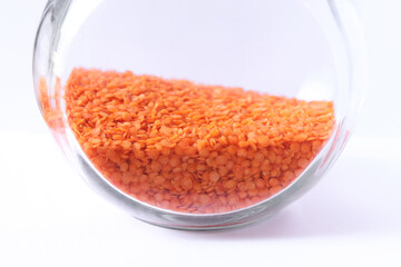 Red lentils in a glass jar isolated on a white background.