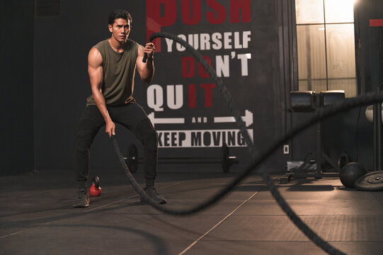 Young Asia sport man with rope doing exercise in functional training fitness gym