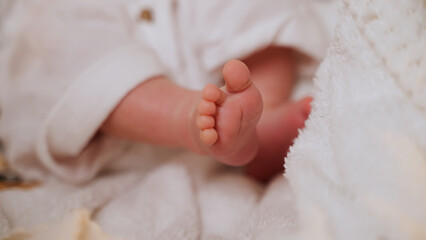 Little tender legs of newborn baby lying on blanket. Child waves legs. Caucasian nationality. Motherhood. Paternity. Happiness to be mom and dad. Continuation of genus. Love and concern. Soft focus
