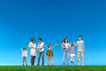 青空を背景に楽しそうにする子供のいる2家族。家族愛,育児イメージ