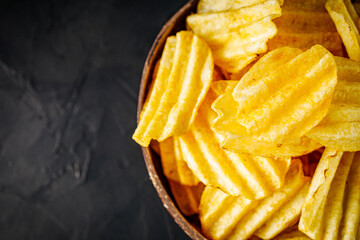 golden crispy potato chips on a dark background