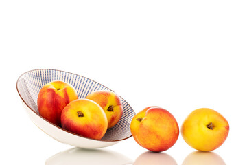 Several juicy organic nectarines with a ceramic plate, close-up, isolated on a white background.