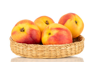 Several juicy organic nectarines with a straw basket, close-up, isolated on a white background.