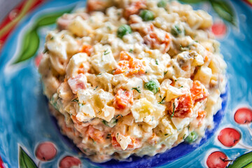 Traditional Ukrainian or Russian salad called olivie olivier macro closeup texture with boiled chopped potatoes, carrots, peas and onions in mayonnaise serving on plate