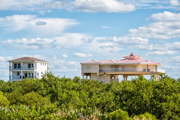 Colorful stilted vacation oceanfront waterfront homes houses on stilts of Atlantic ocean beach by mangrove forest in summer of Palm Coast on Crescent Beach, Florida © Kristina Blokhin