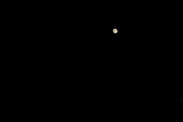 Small tiny full moon planet in clear dark black sky in Southwest Florida at Naples