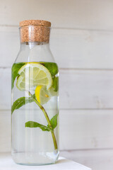 Mint and lemon in water. Mint leaves and lemon slices in bottle on white background. Antioxidant drink. Fresh summer drinks. Homemade citrus water. Lemonade with lemon and mint. Iced beverage. - 513551898