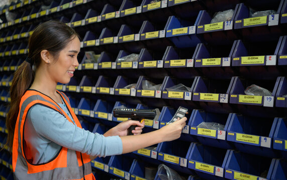 Female warehouse worker Counting small parts stored in the blue storage compartment. to check the remaining amount in order to prepare for the next order