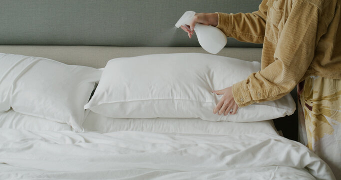 Woman use spray for clean the bed at home